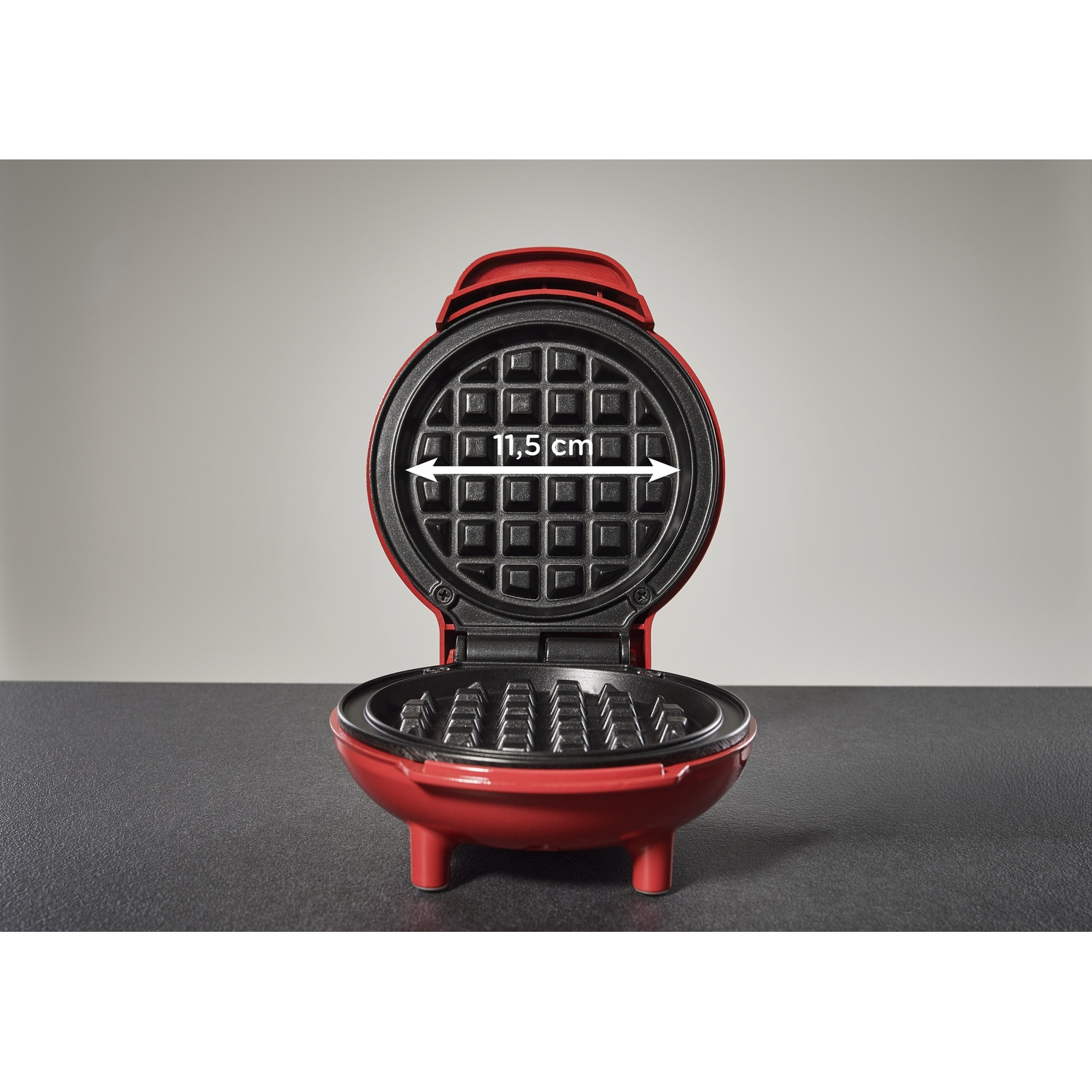 Mini piastra per waffle rossa aperta con misura 11,5 cm.