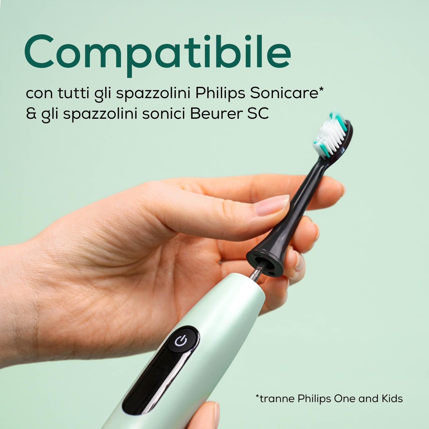 Una mano tiene un corpo di spazzolino verde chiaro e una testina nera con setole bianche e turchesi.