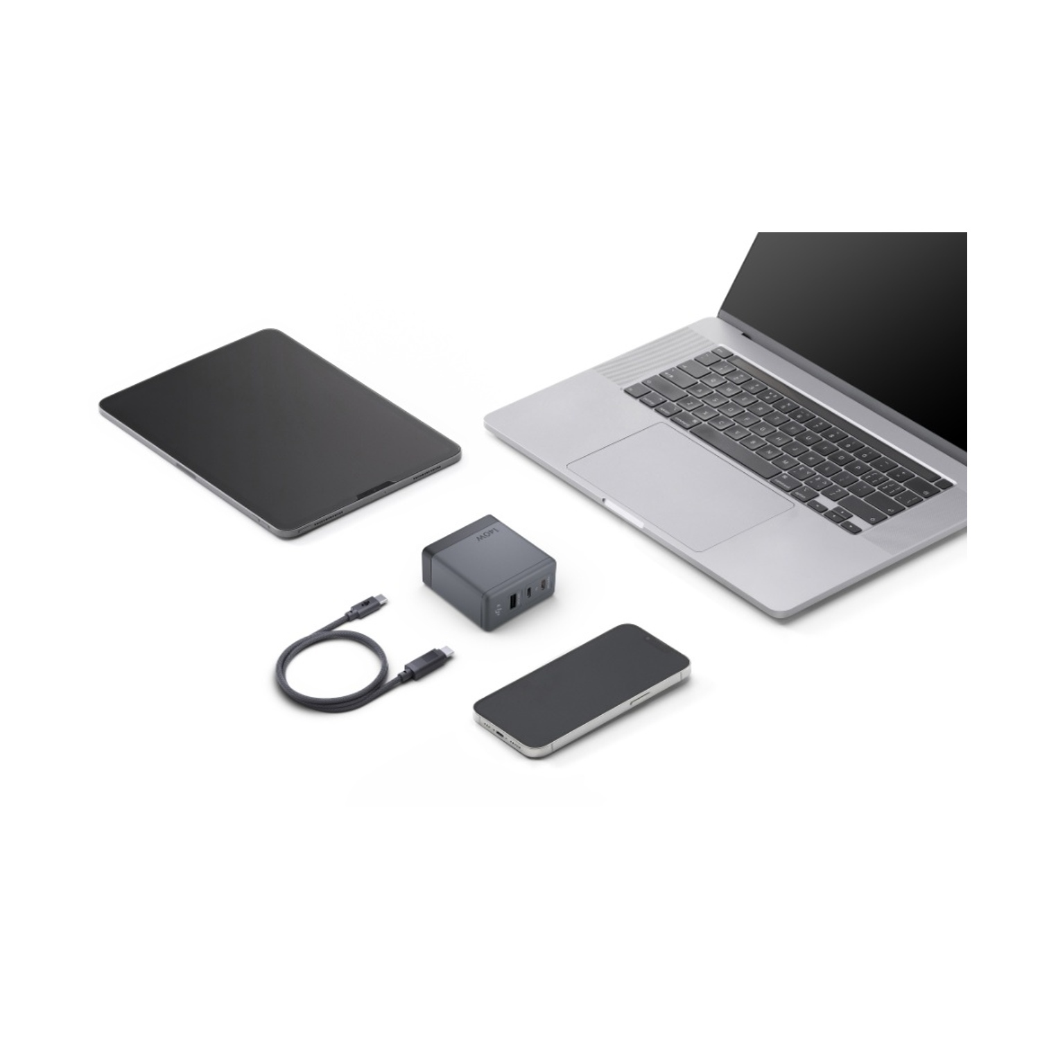Un computer portatile, un tablet, uno smartphone, un adattatore e un cavo USB-C su una superficie bianca.