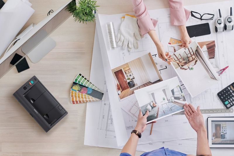 I designer lavorano a una scrivania con progetti, campioni di colore e foto.