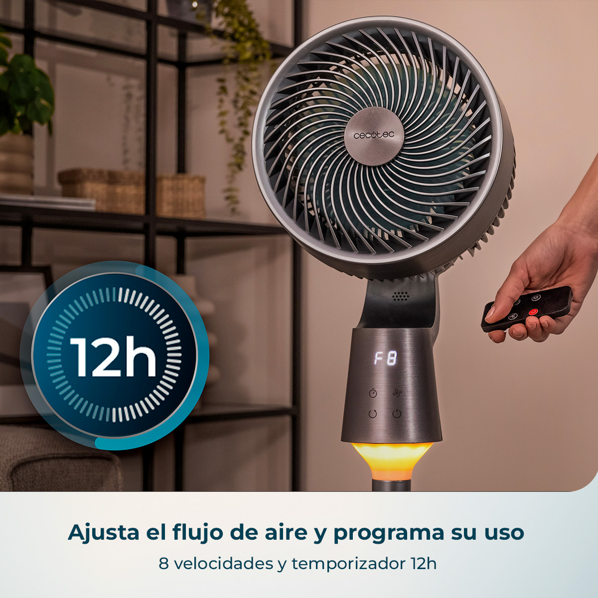 Ventilador de pie gris Cecotec con mando, pantalla digital y luz cálida ante una estantería.