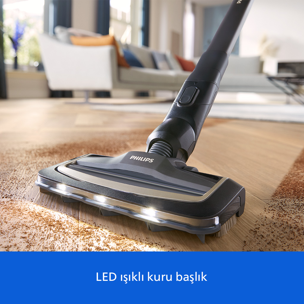 LED ışıklı Philips süpürge başlığı, aydınlık bir oturma odasında ahşap zemindeki kirleri temizliyor.