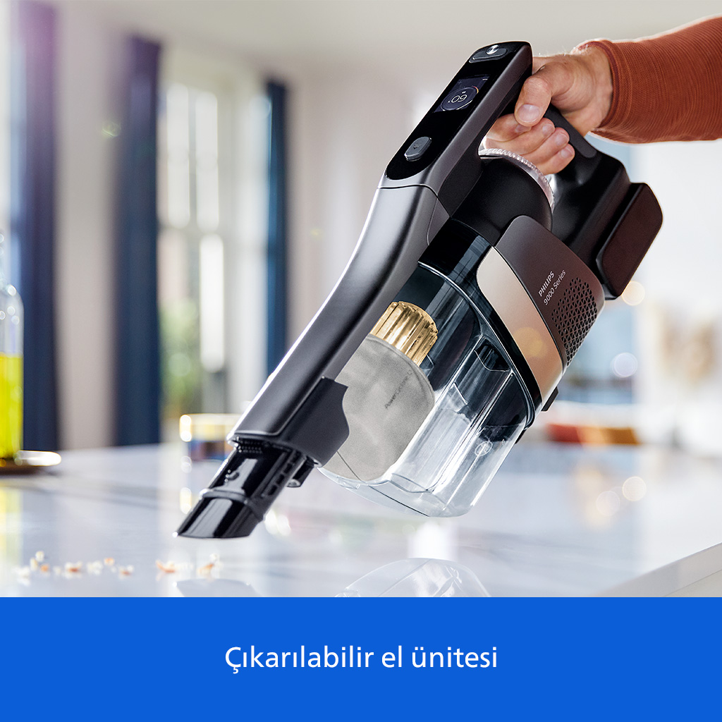 Bir el, kırıntılı mutfak tezgahının üzerinde kablosuz bir Philips elektrikli süpürge tutuyor.