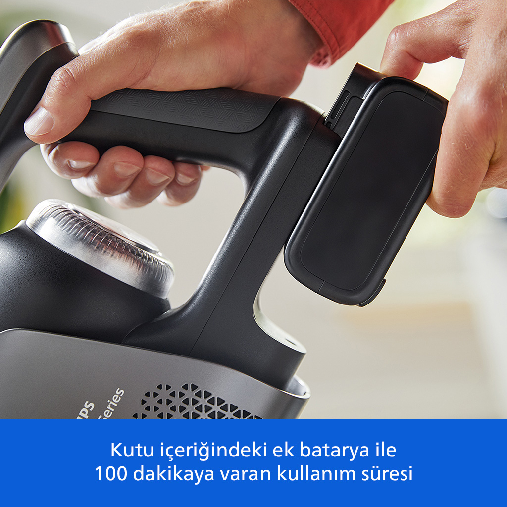 Eller ek bataryalı siyah bir elektrikli süpürgeyi tutuyor.