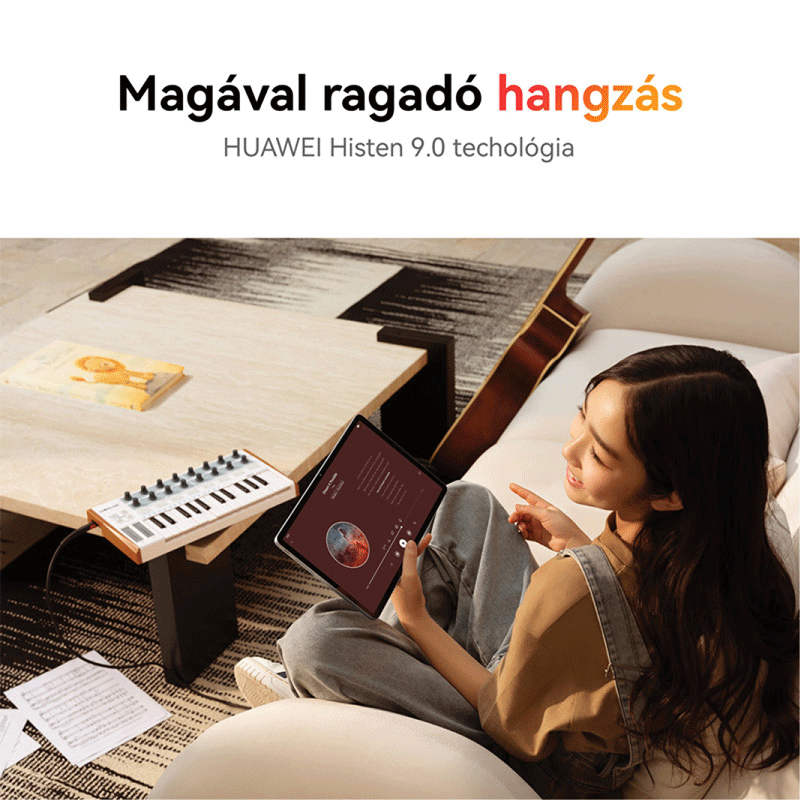 Egy fiatal nő a kanapén ül, tablettel a kezében, billentyűzettel és gitárral.