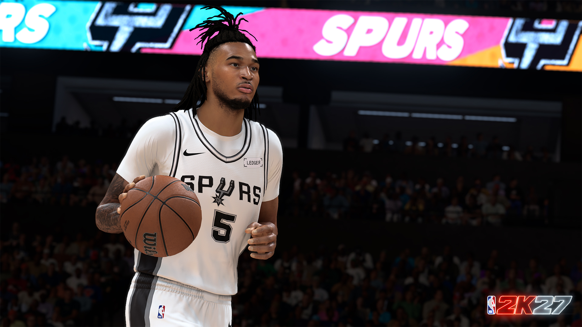 Un jugador de baloncesto con camiseta blanca y negra de los Spurs regatea el balón en un estadio lleno.