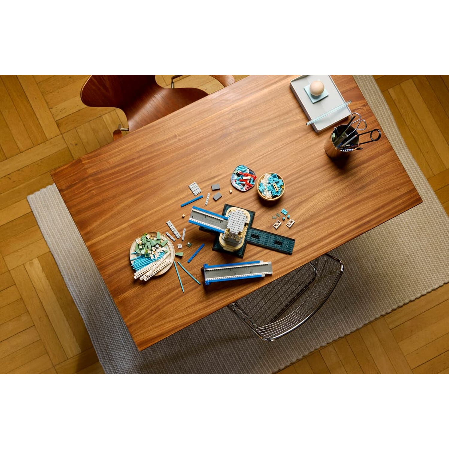 Vista dall'alto di un tavolo in legno con un set Lego parzialmente costruito, ciotole e accessori.