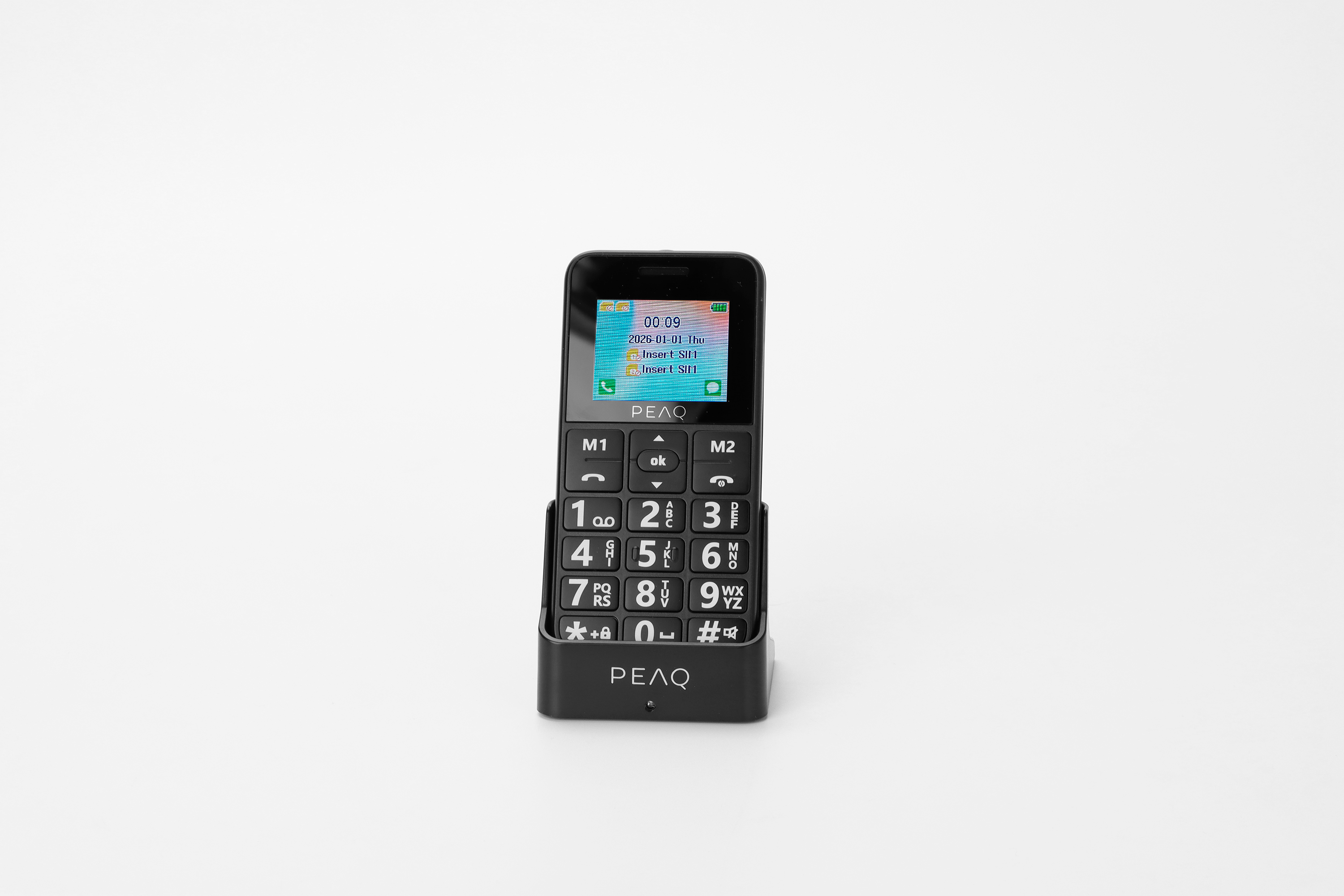 Ein schwarzes Seniorenhilfe-Tastentelefon mit Ladeschale auf hellem Hintergrund.