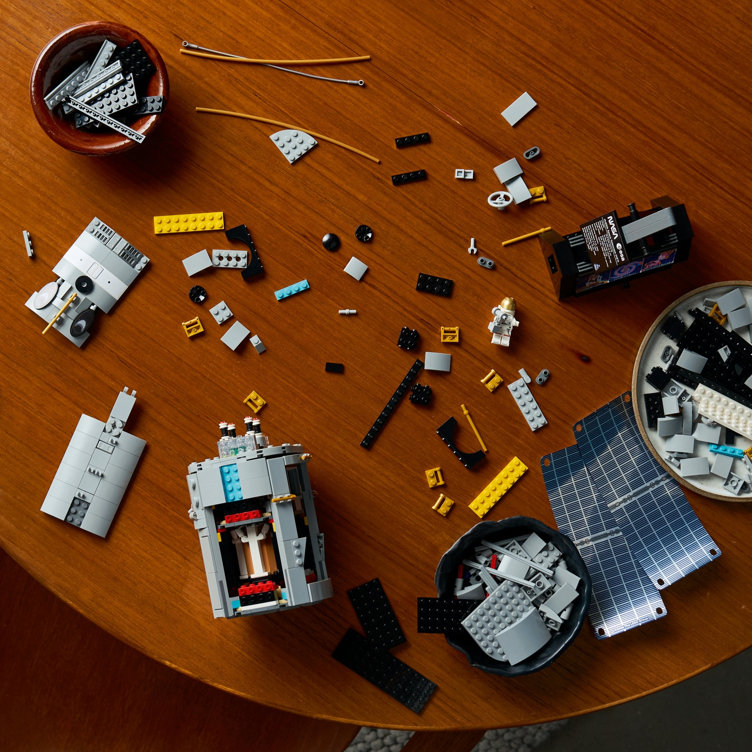 Vari pezzi Lego e costruzioni parziali sono sparsi su un tavolo rotondo di legno.