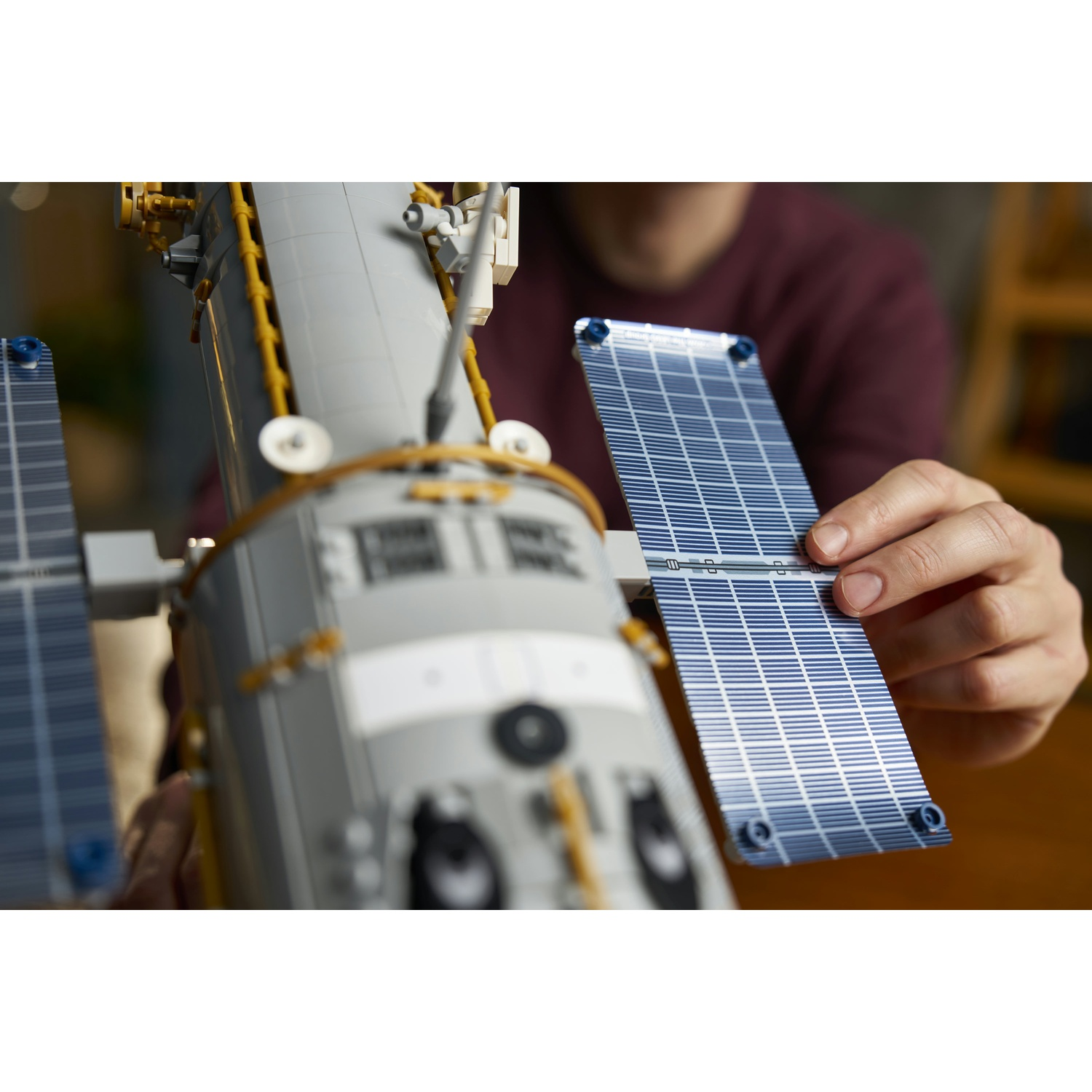 Una persona costruisce un modello Lego della stazione spaziale ISS tenendo un pannello solare.
