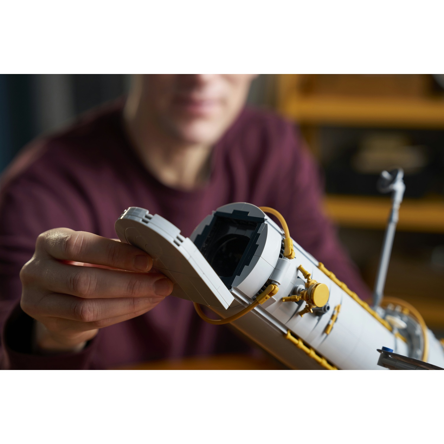 Una persona costruisce un modello LEGO bianco e oro mentre apre il coperchio.