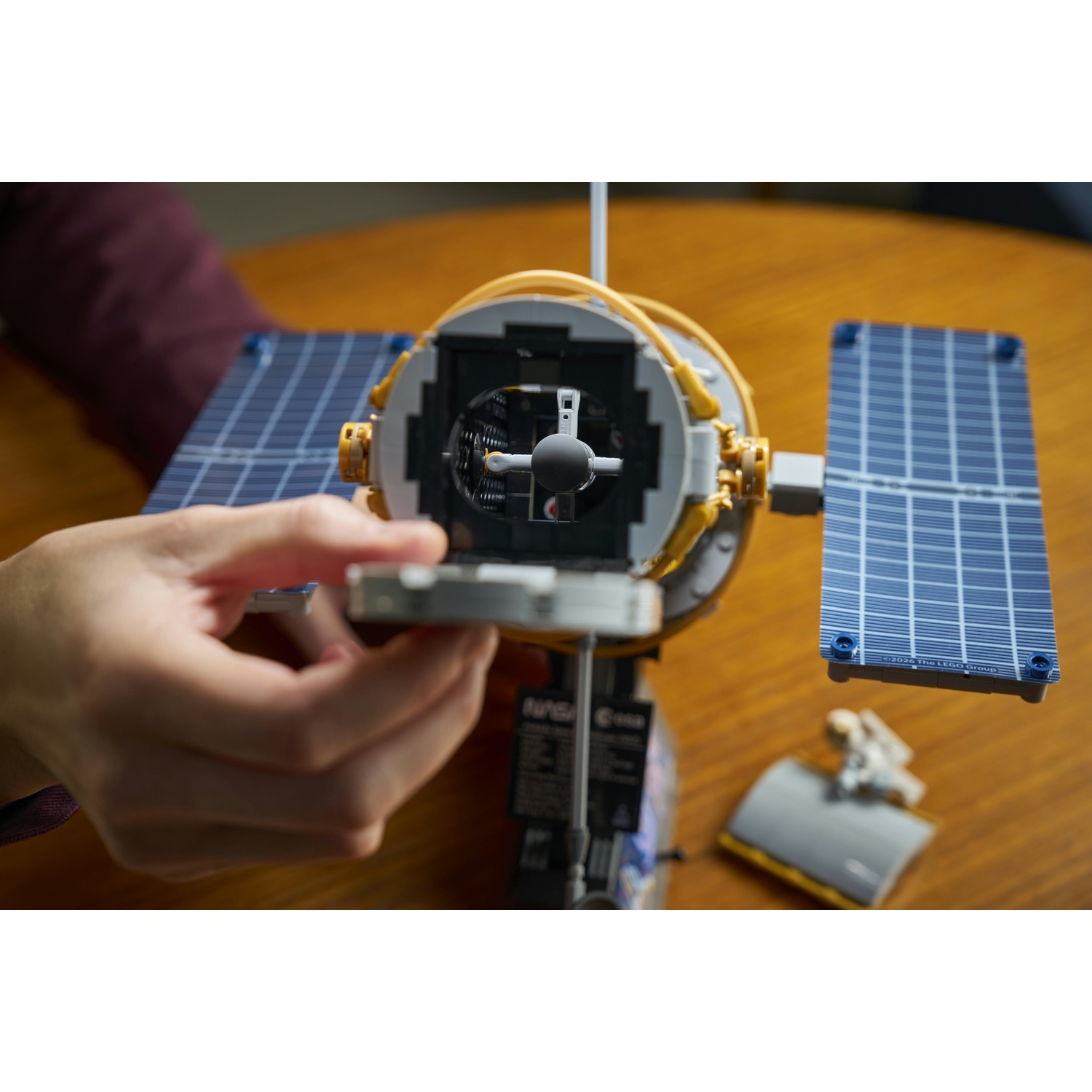 Una mano assembla un dettagliato modello di veicolo spaziale Lego con pannelli solari blu.