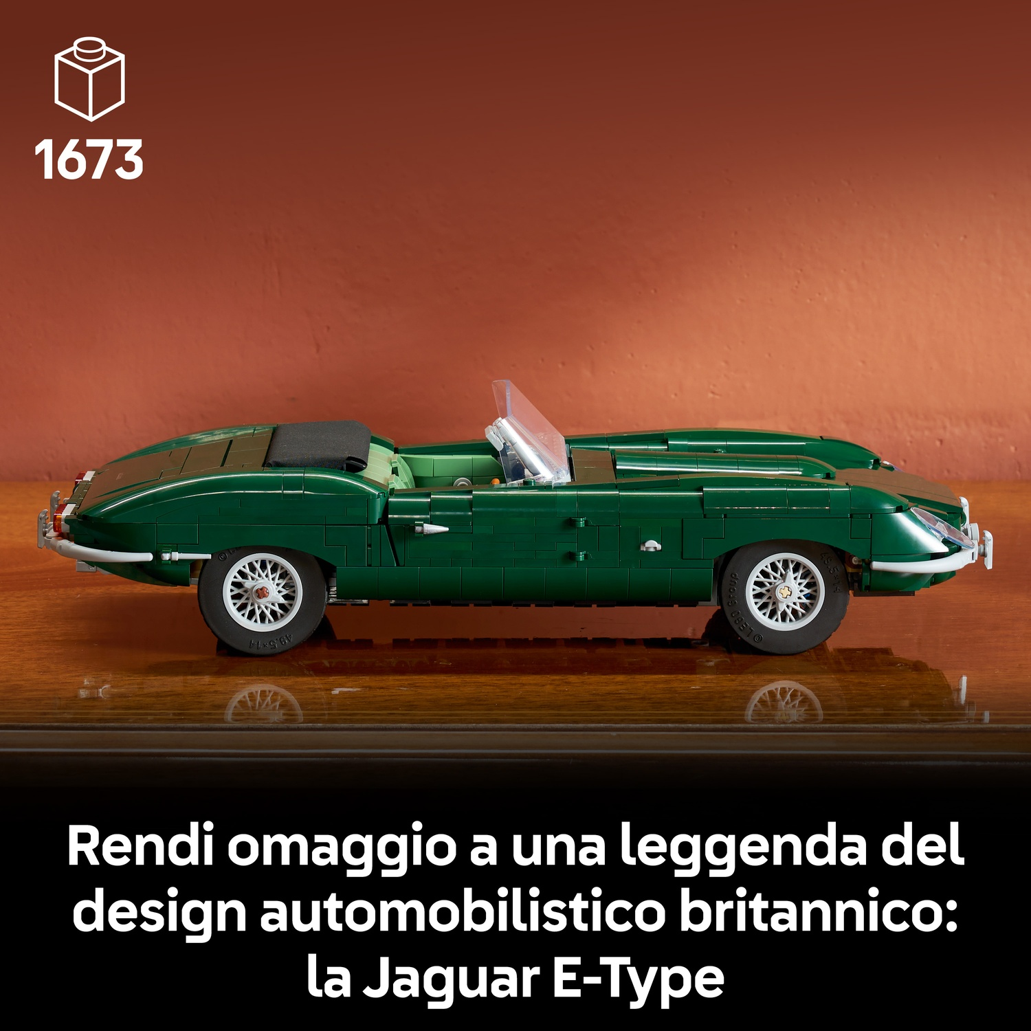 Un'auto modello Lego Jaguar E-Type verde è su un tavolo di legno davanti a una parete rossa.