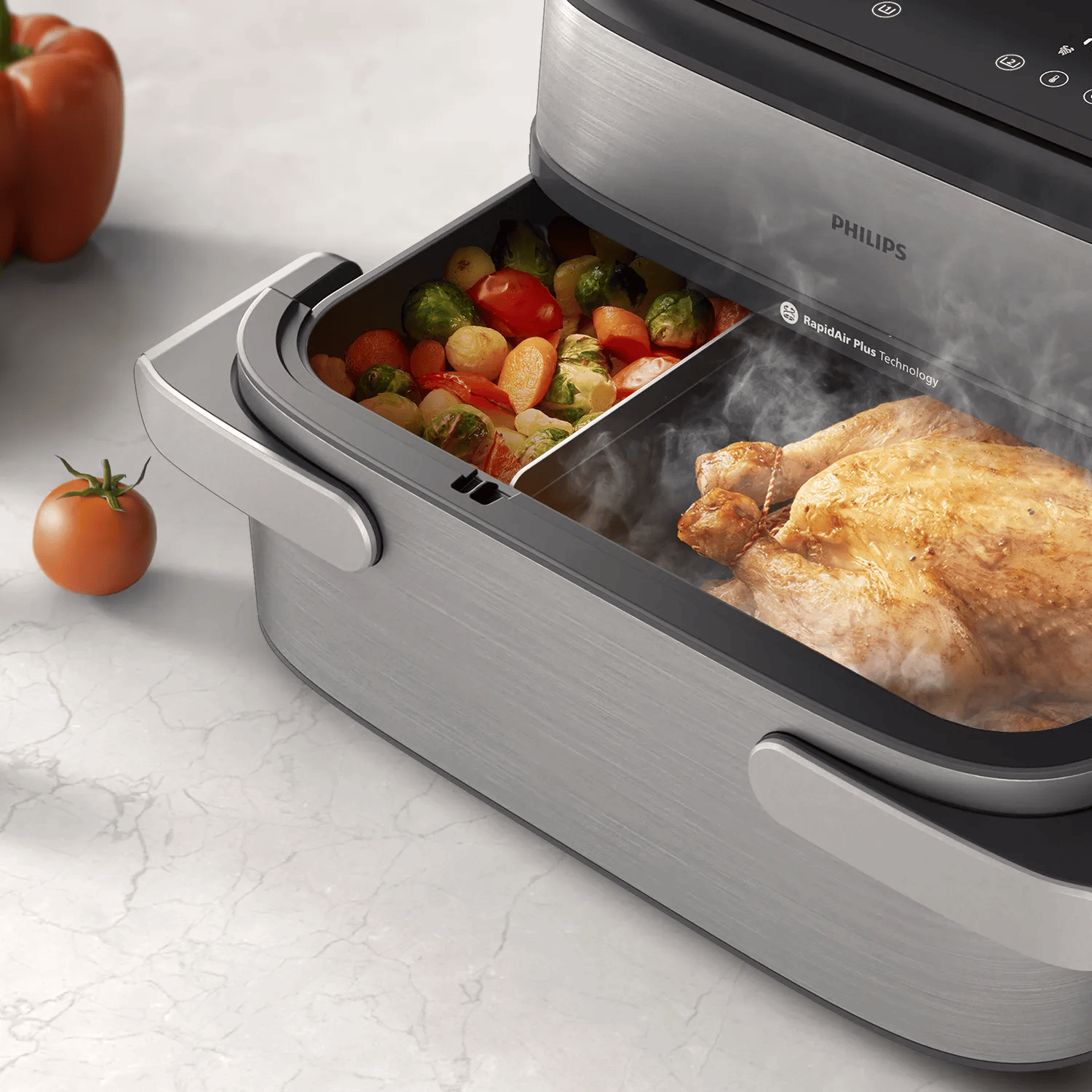 Une friteuse sans huile Philips avec un panier ouvert contenant du poulet rôti et des légumes.