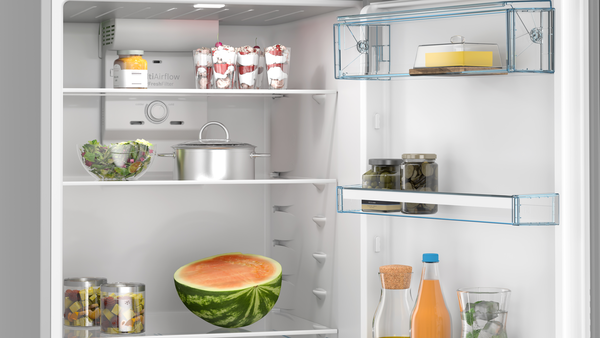 Salata, tatlılar, sebzeler, kavanozlar, içecekler ve yarım karpuz gibi yiyeceklerle dolu açık beyaz buzdolabı.