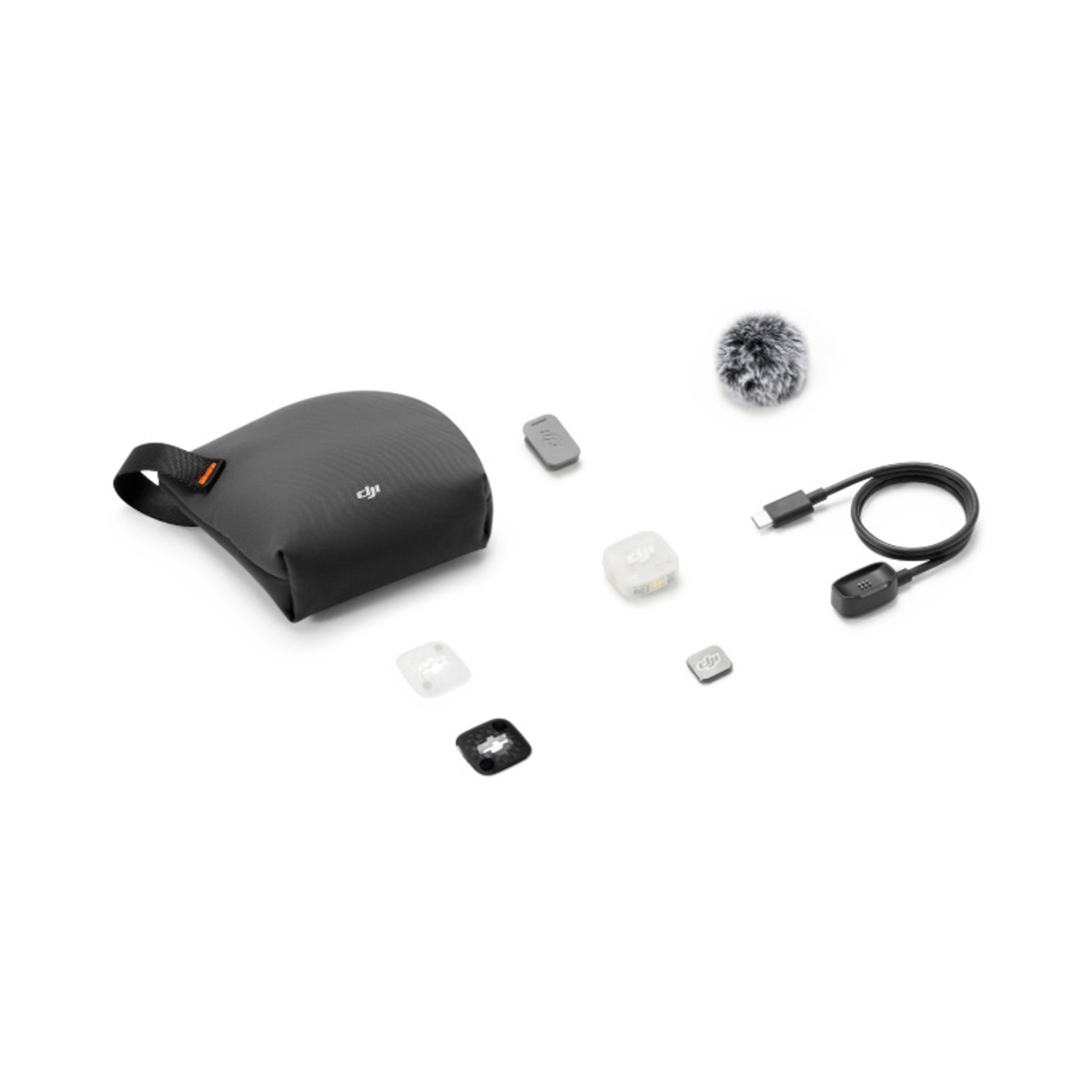 Set accessori microfono DJI con custodia grigia, cavo, cuffia antivento e piccole clip magnetiche su sfondo bianco.