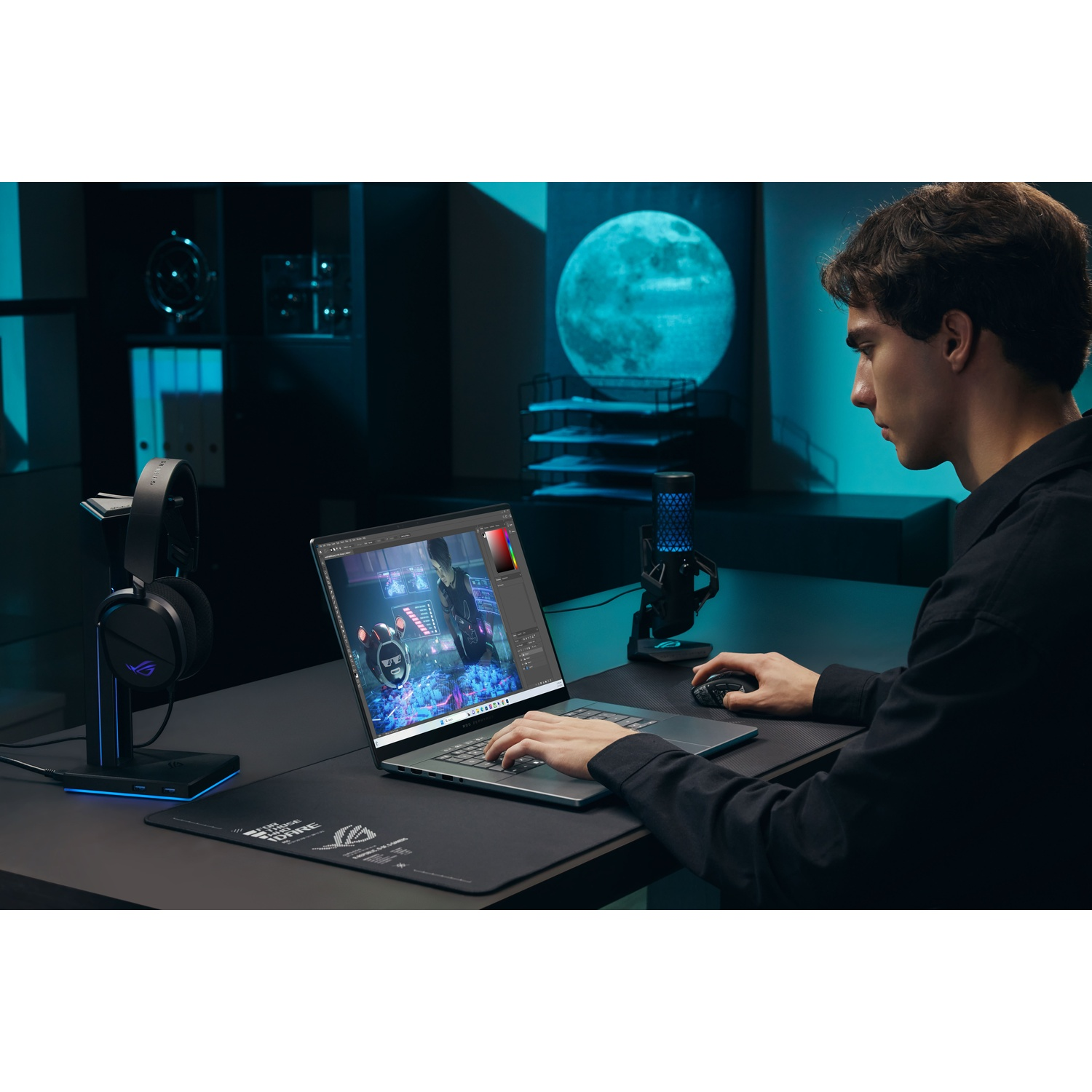 Un uomo in camicia scura lavora su un laptop in una stanza illuminata di blu, con cuffie e microfono.