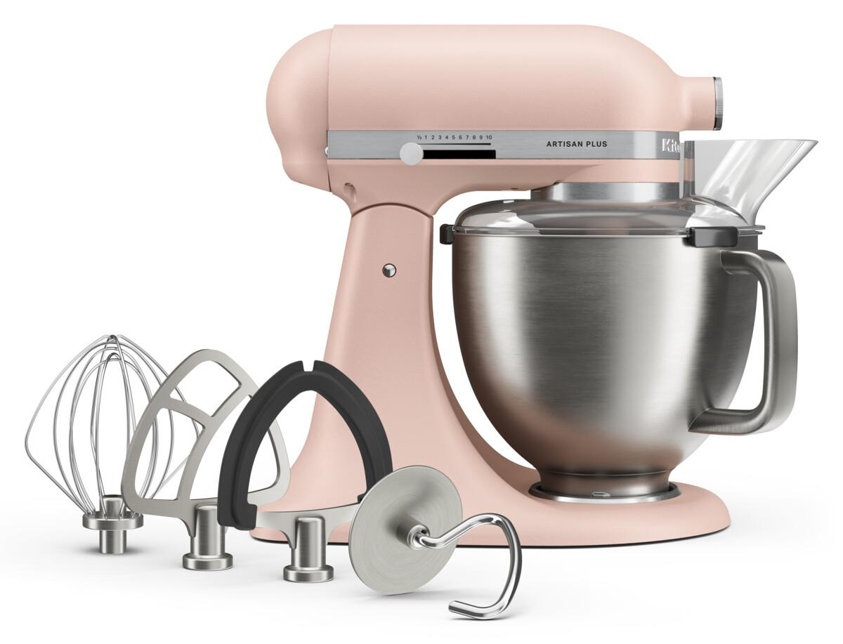 Rosa Artisan Plus Küchenmaschine mit Edelstahl-Rührschüssel und vier verschiedenen Rühraufsätzen davor.