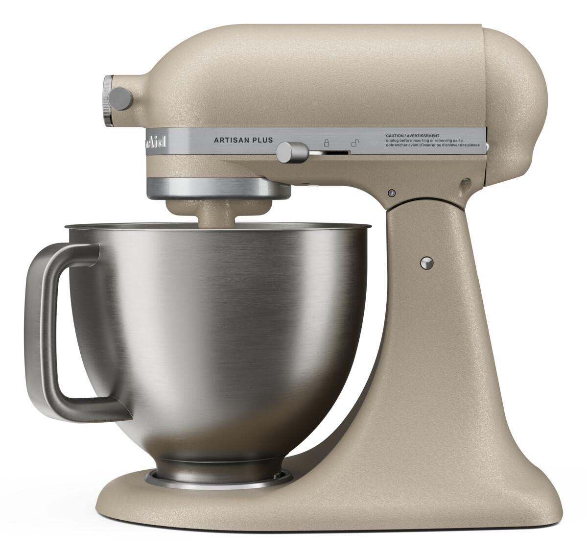 Ein beiger KitchenAid Artisan Plus Standmixer mit einer Edelstahlschüssel auf weißem Hintergrund.