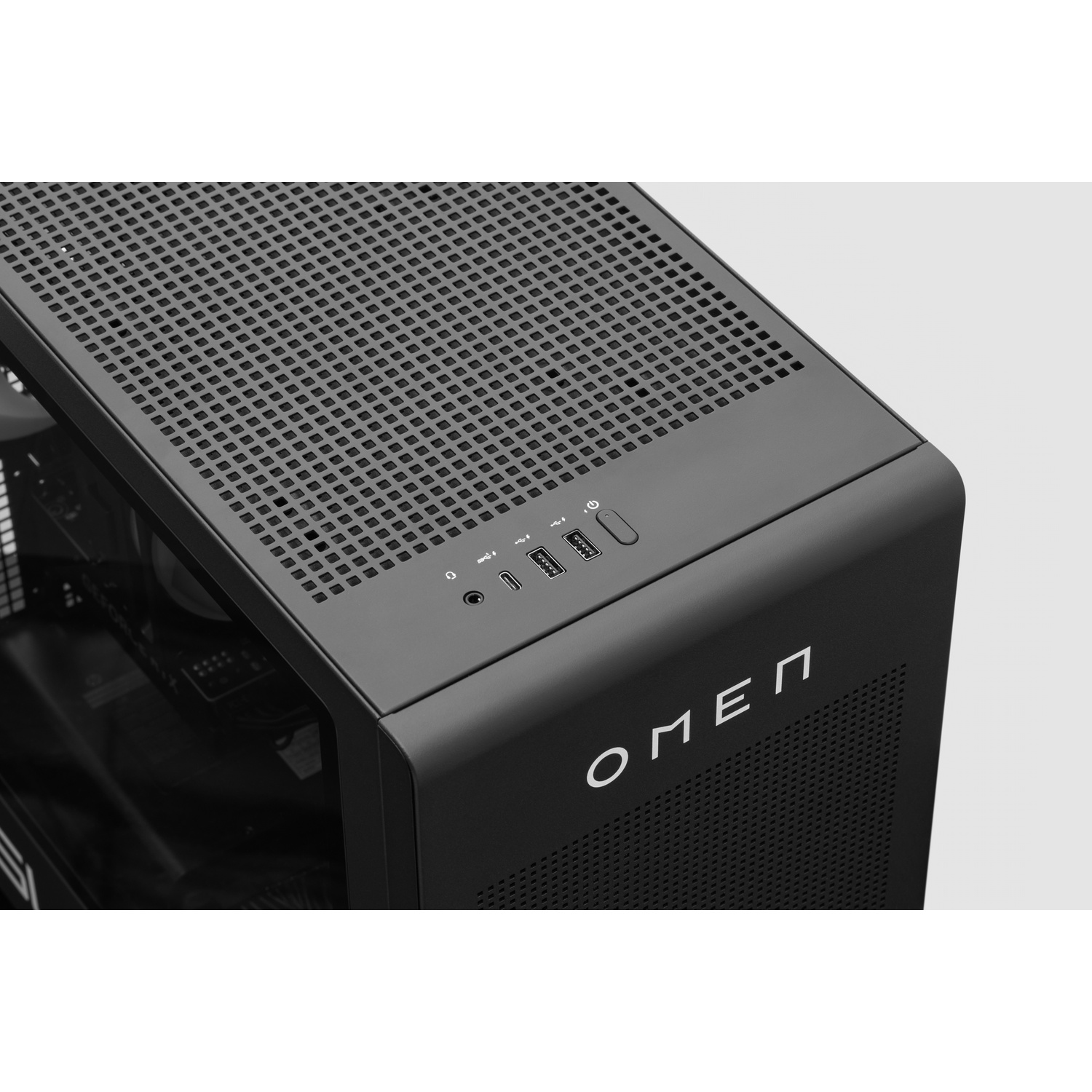 Close-up van de bovenkant van een zwarte HP Omen desktop PC met een geperforeerd rooster en USB-poorten.
