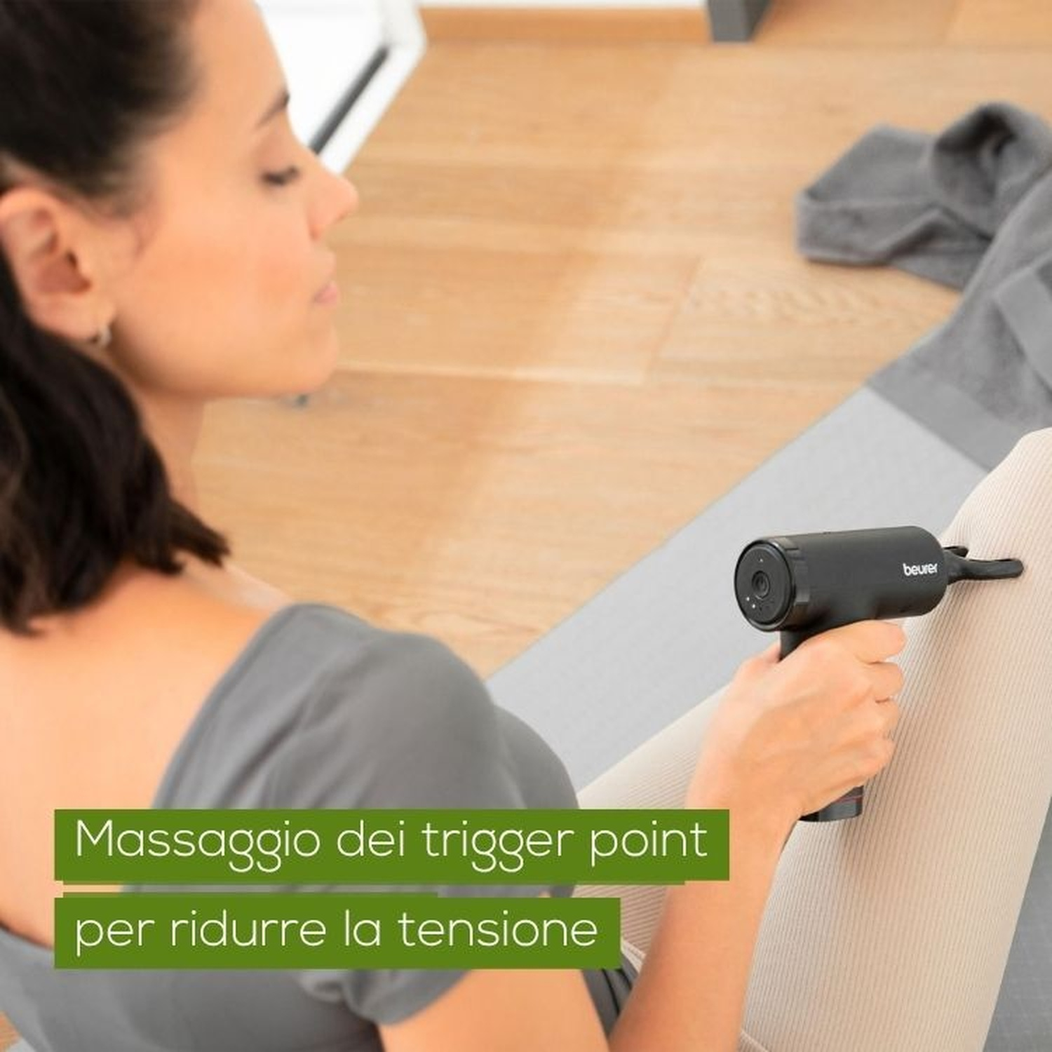 Una donna usa una pistola massaggiante nera sulla gamba per alleviare la tensione.