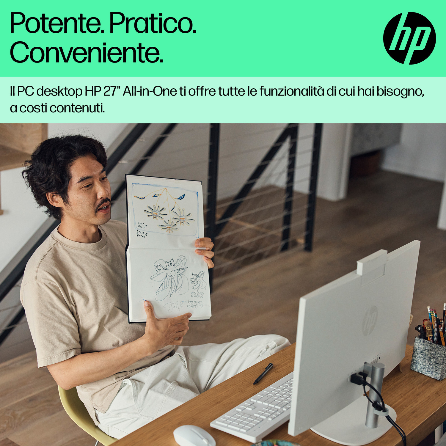Un uomo mostra schizzi in un quaderno davanti a un PC HP All-in-One bianco a una scrivania.