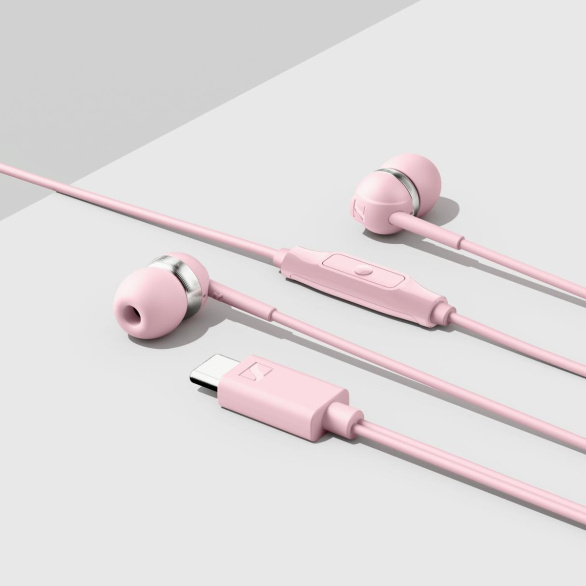 Rózsaszín vezetékes fülhallgató USB-C csatlakozóval szürke felületen.