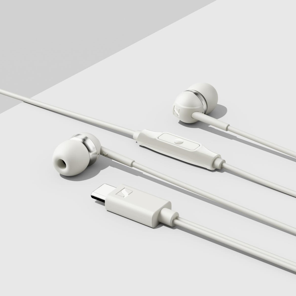 Fehér vezetékes fülhallgató beépített távirányítóval és USB-C csatlakozóval egy fehér felületen.