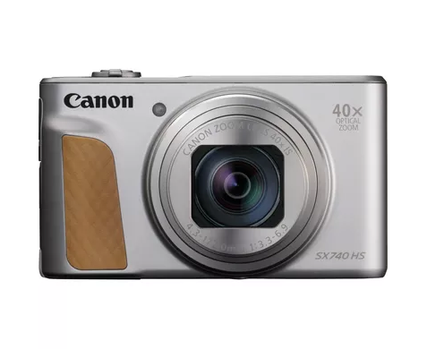 Srebrny aparat kompaktowy Canon SX740 HS z brązowym uchwytem na białym tle.