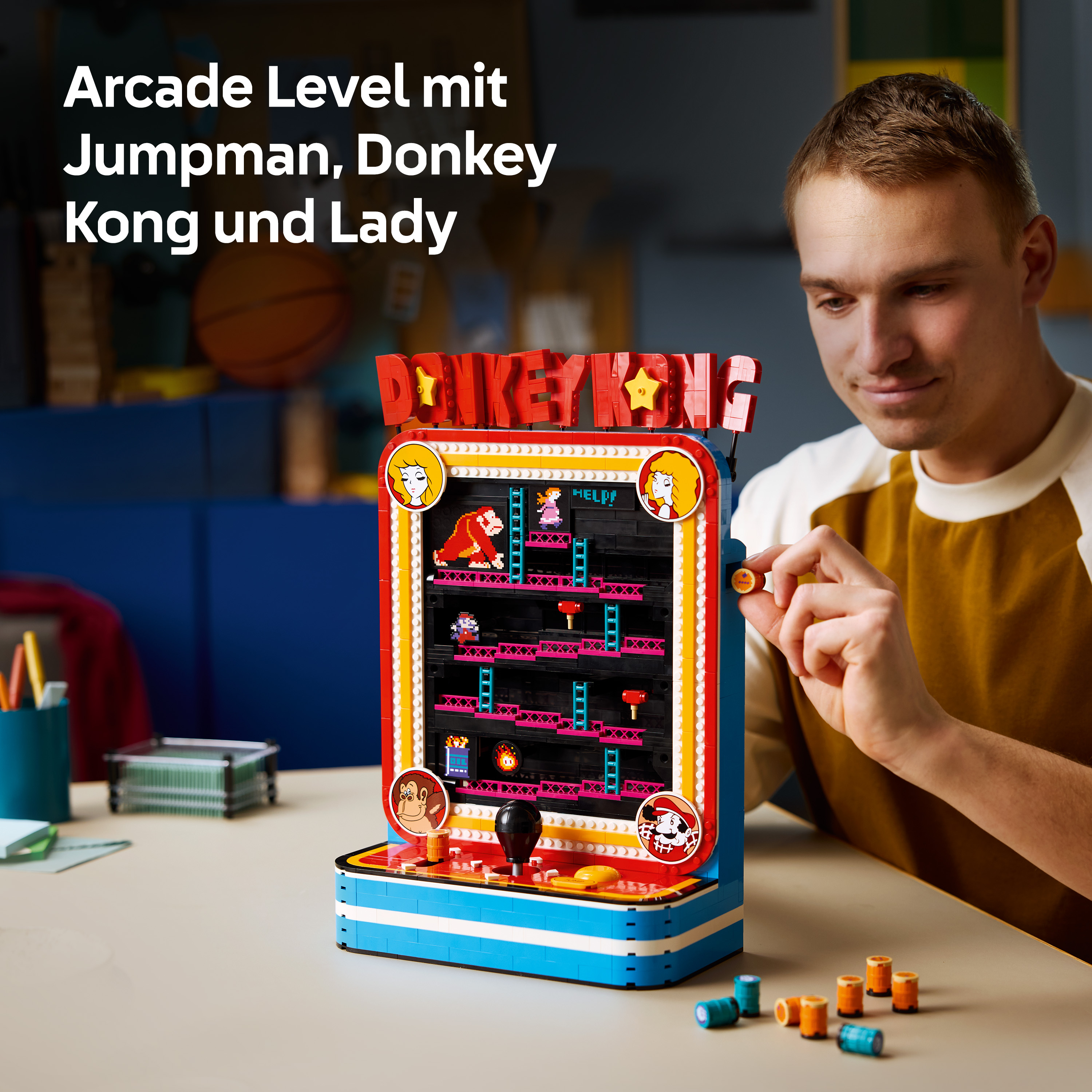 Ein Mann baut ein farbenfrohes Lego-Donkey-Kong-Arcade-Spiel auf einem Tisch zusammen.