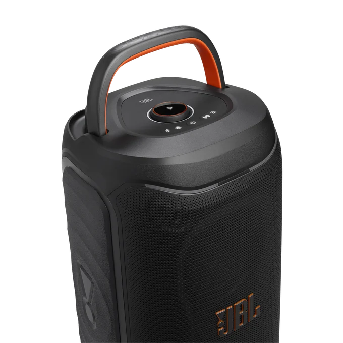 Un altavoz portátil JBL negro con asa naranja y botones de control arriba sobre fondo negro.