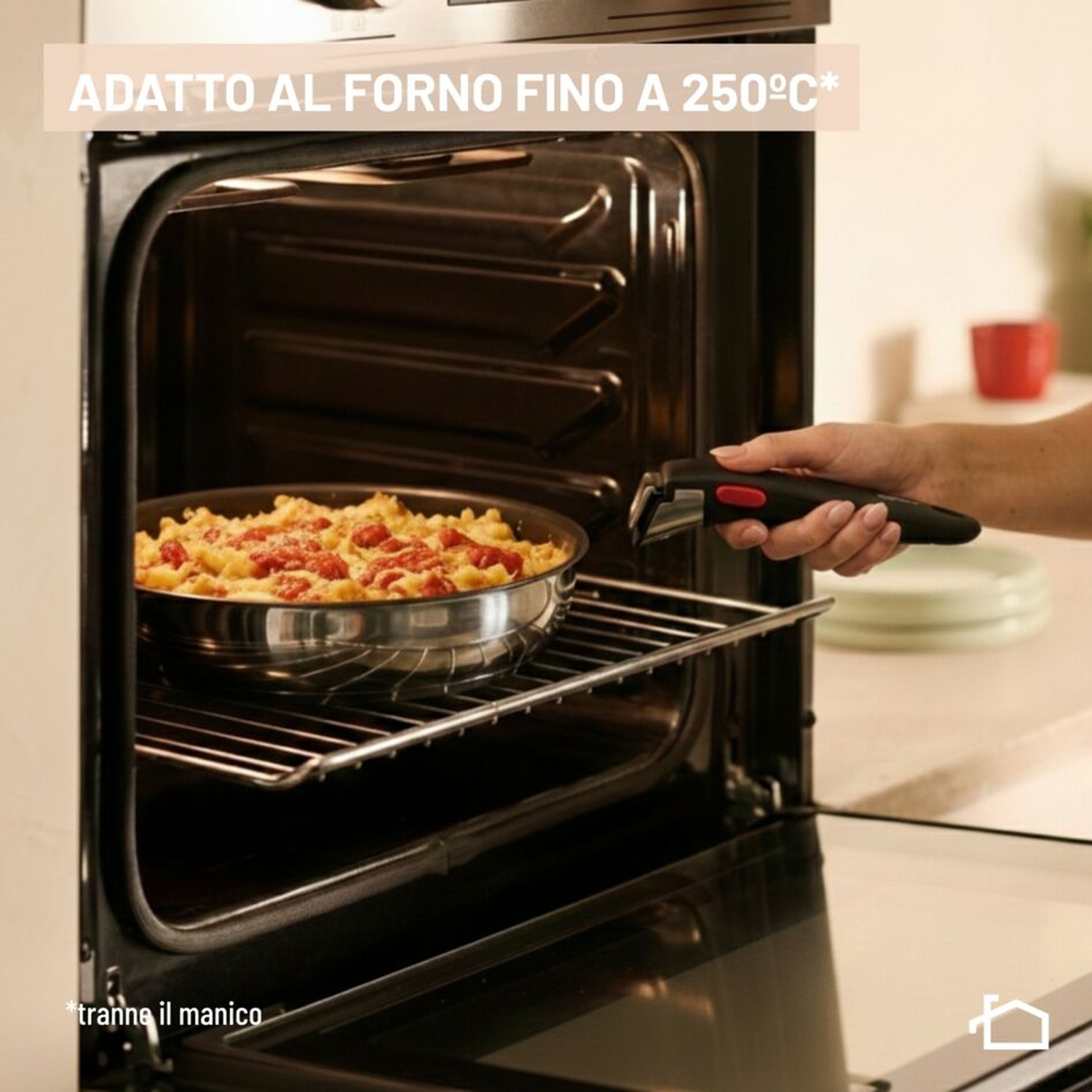 Una mano inserisce una padella di pasta al forno nel forno.