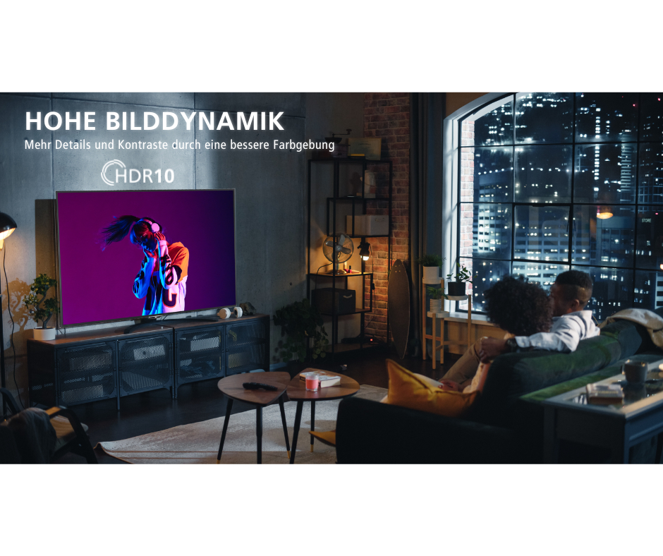 Ein Paar sitzt auf einem Sofa und schaut in einem modernen Wohnzimmer mit großem Fenster fern.