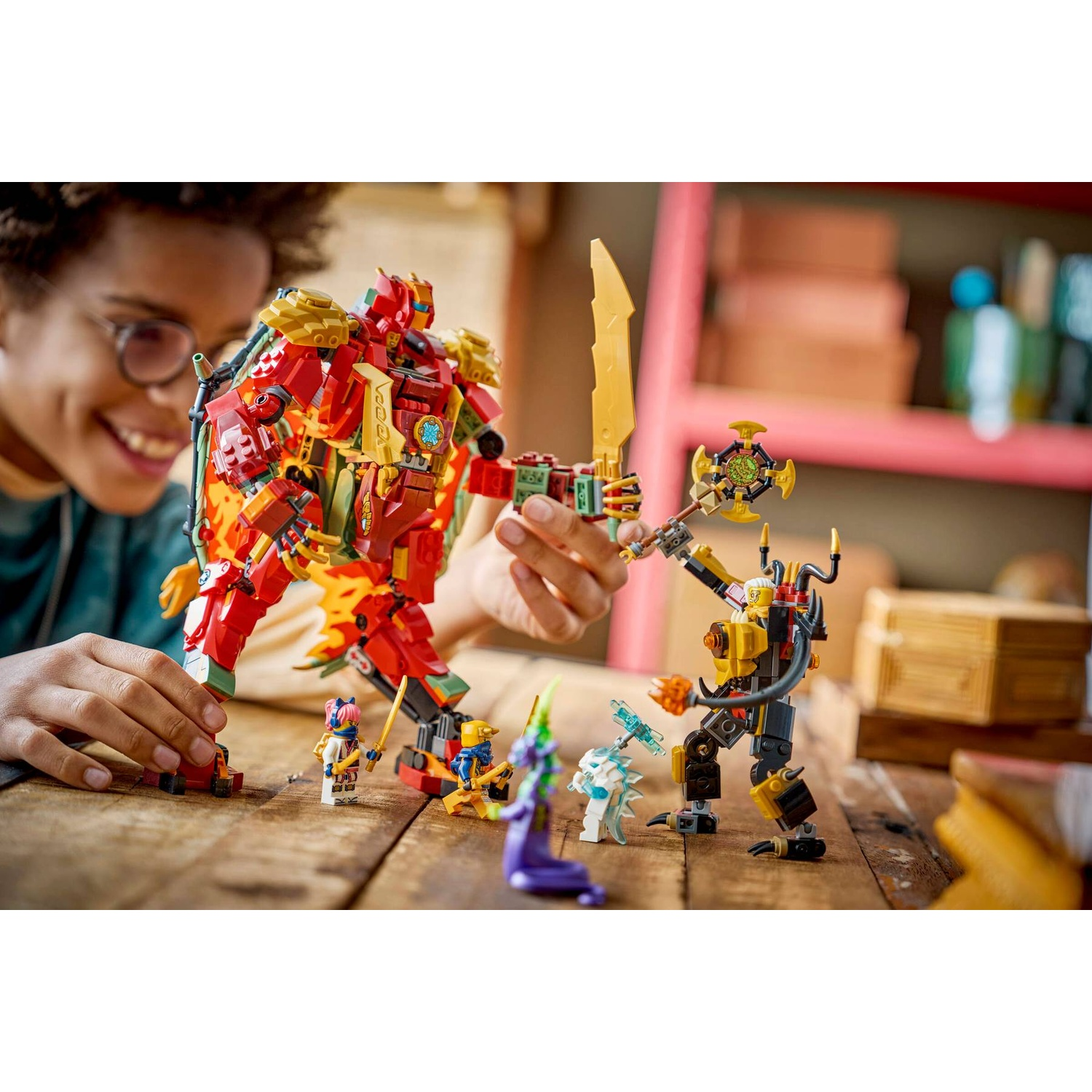 Un bambino gioca felicemente con colorati robot Lego e minifigure su un tavolo di legno.