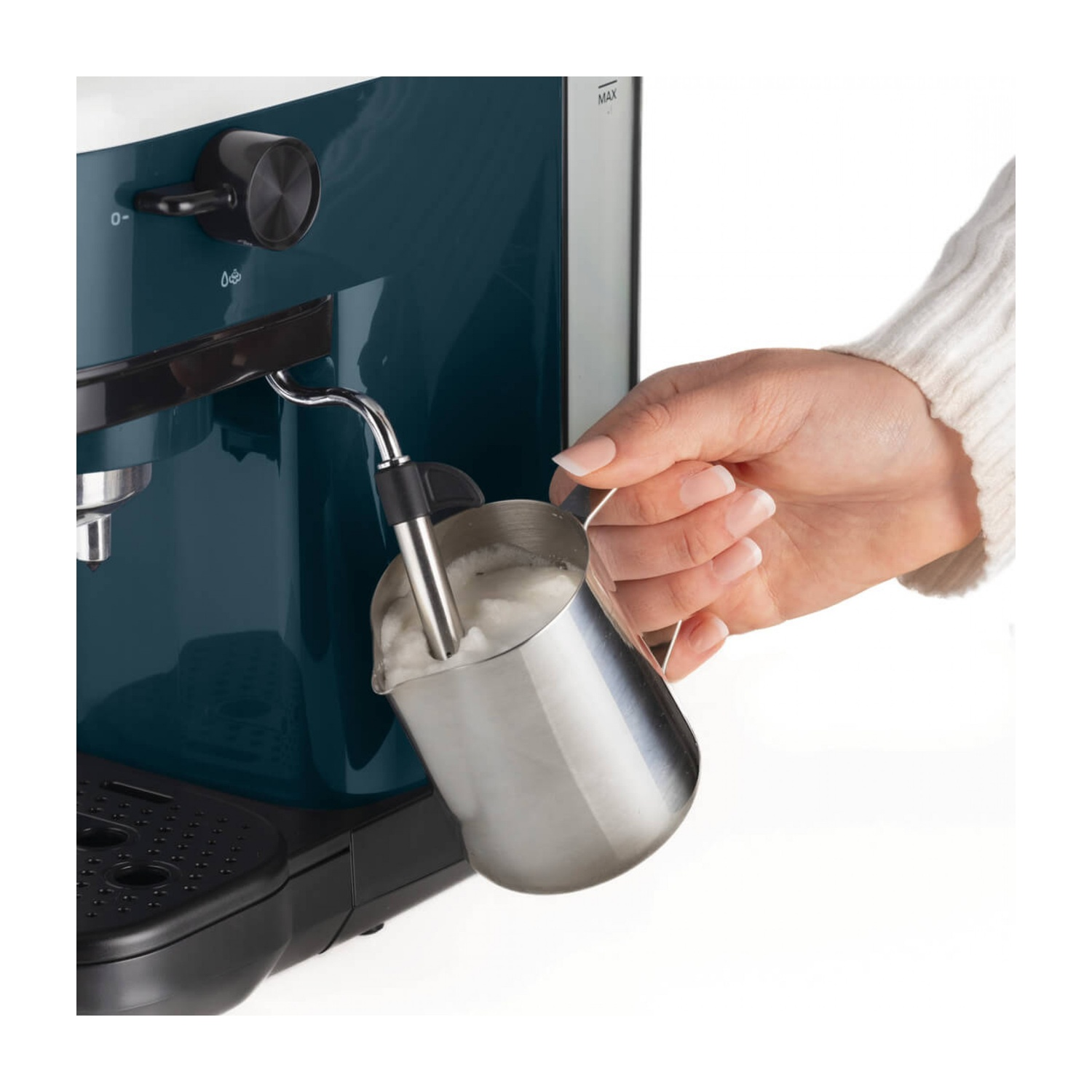 Una mano regge una lattiera sotto il beccuccio del vapore di una macchina da caffè blu.