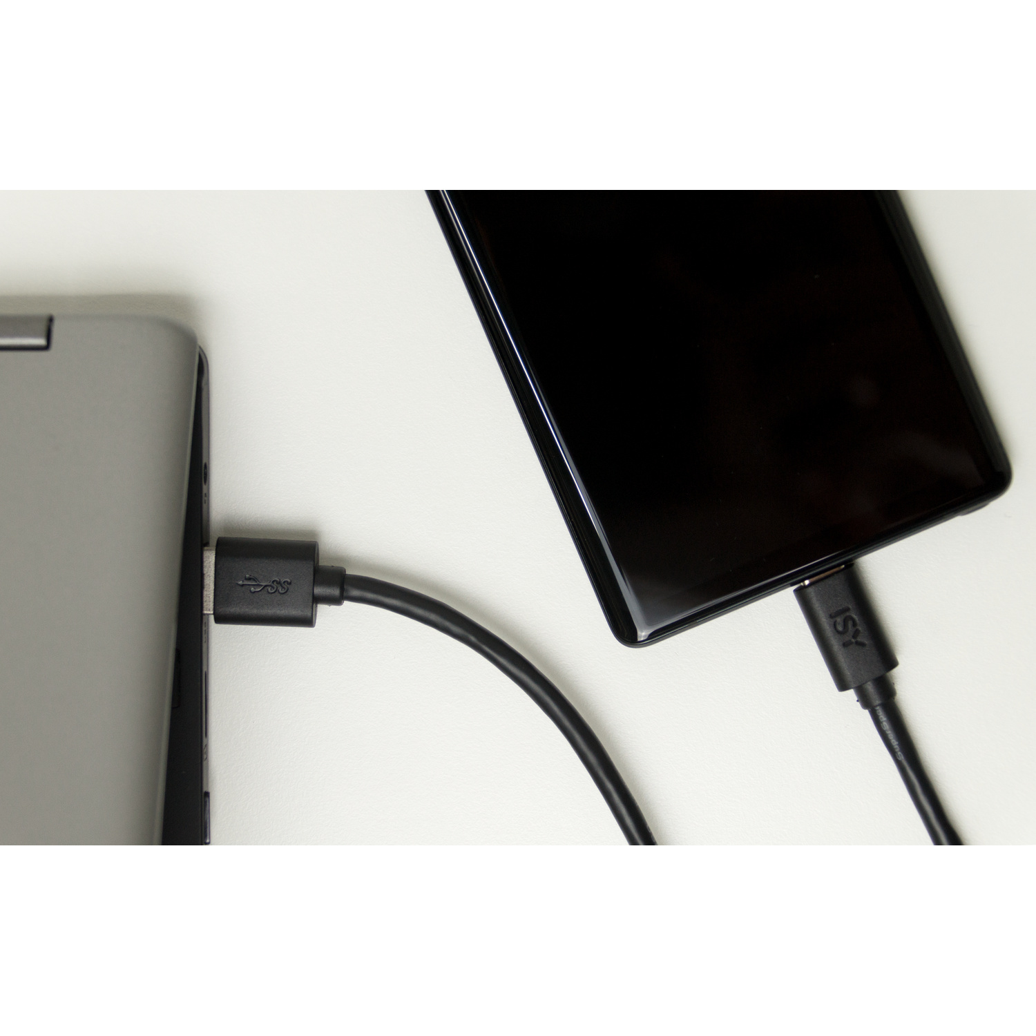 Uno smartphone e un computer portatile sono collegati su una superficie bianca tramite un cavo USB nero.