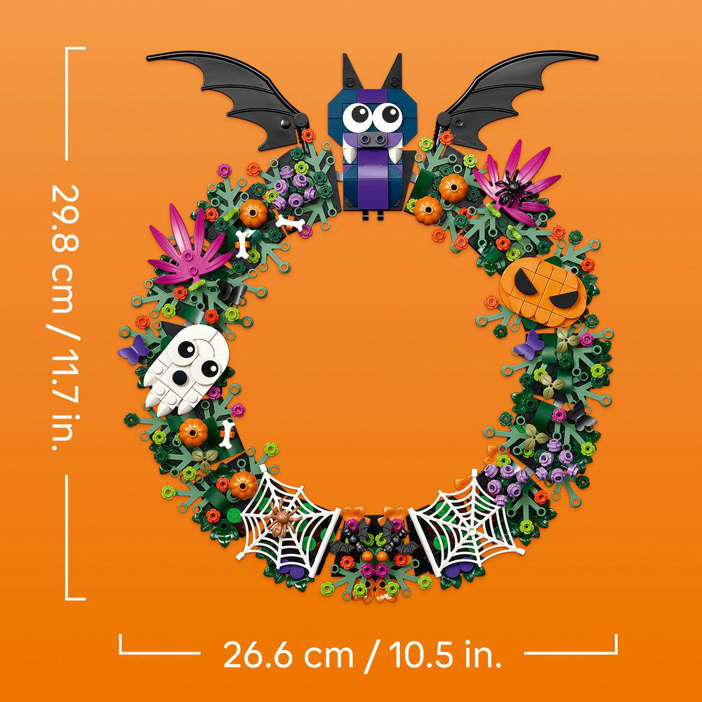 Halloween-Blumenkranz aus LEGO-Steinen mit Fledermaus, Kürbissen, Knochen und Spinnenweben auf orangefarbenem Grund.