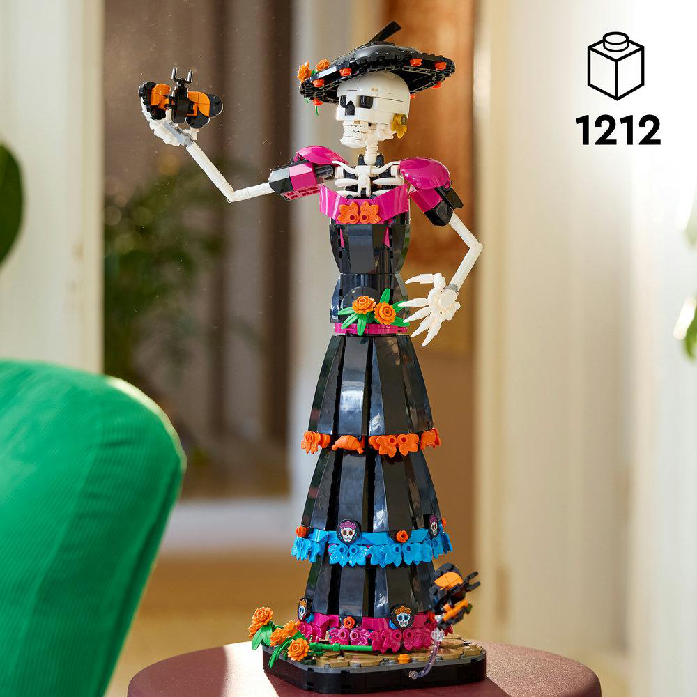 Lego-Skelettfigur im bunten Kleid hält einen Schmetterling.