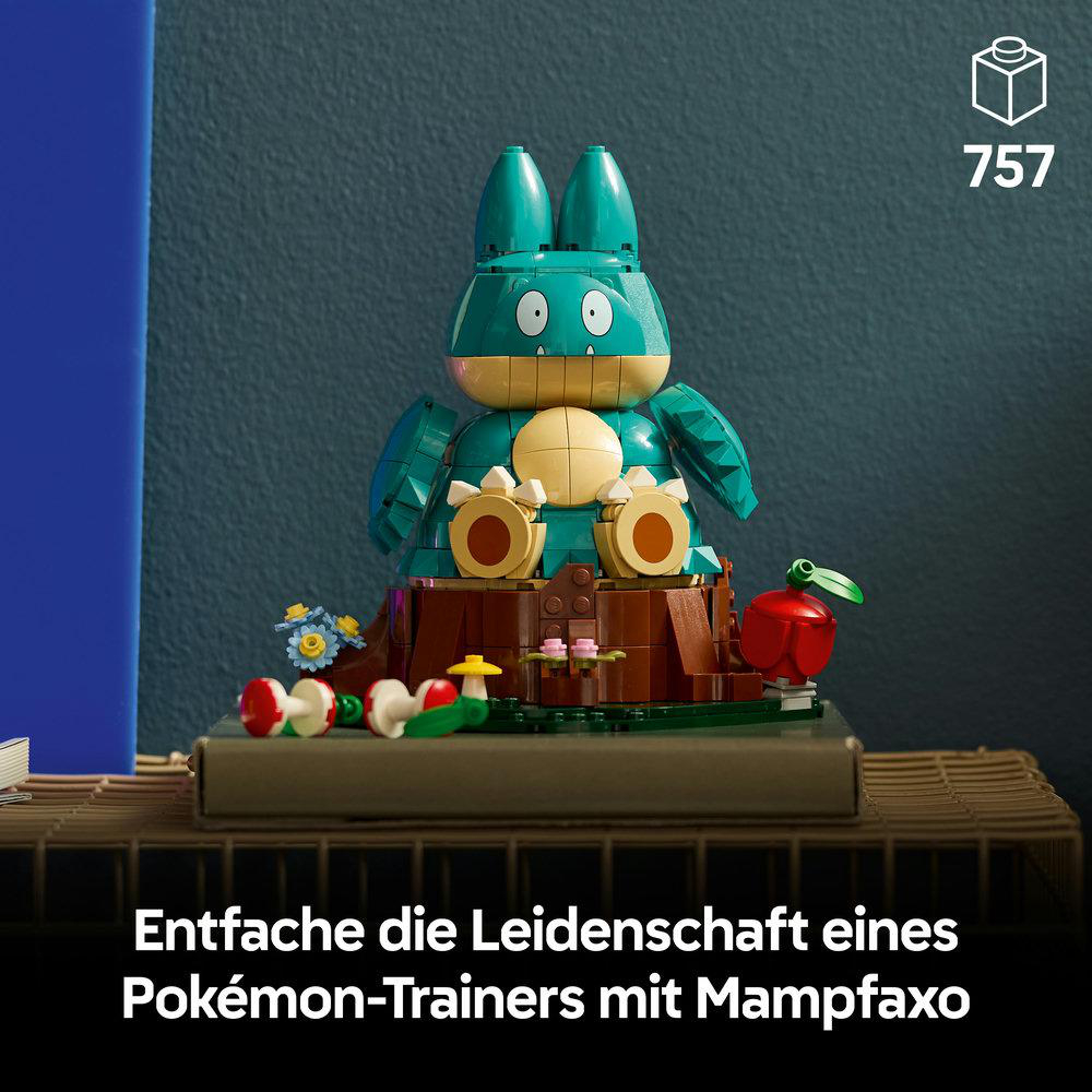 Ein grün-gelbes Pokémon-Modell aus Lego-Steinen sitzt auf einem Baumstumpf mit Zubehör auf einer holzfarbenen Kiste.