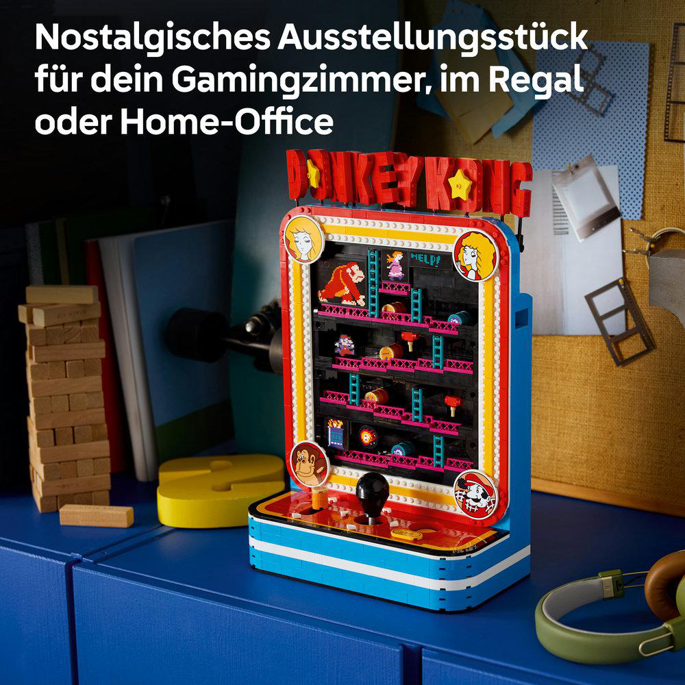 Ein Lego-Donkey Kong Arcade-Automat steht auf einem blauen Tisch mit Gaming-Zubeh ör im Hintergrund.