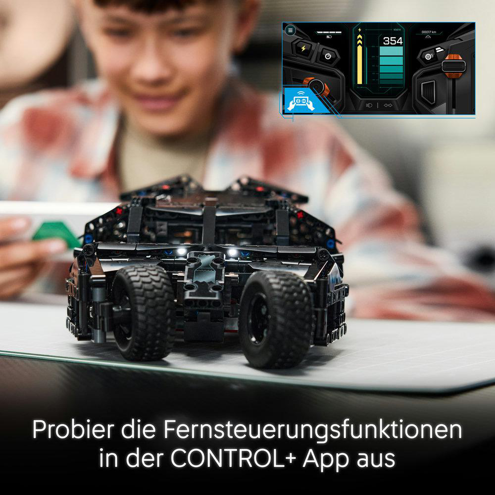 Ein schwarzes Lego Batmobil auf einem Tisch mit einem Kind im Hintergrund und einer digitalen App-Oberfläche.