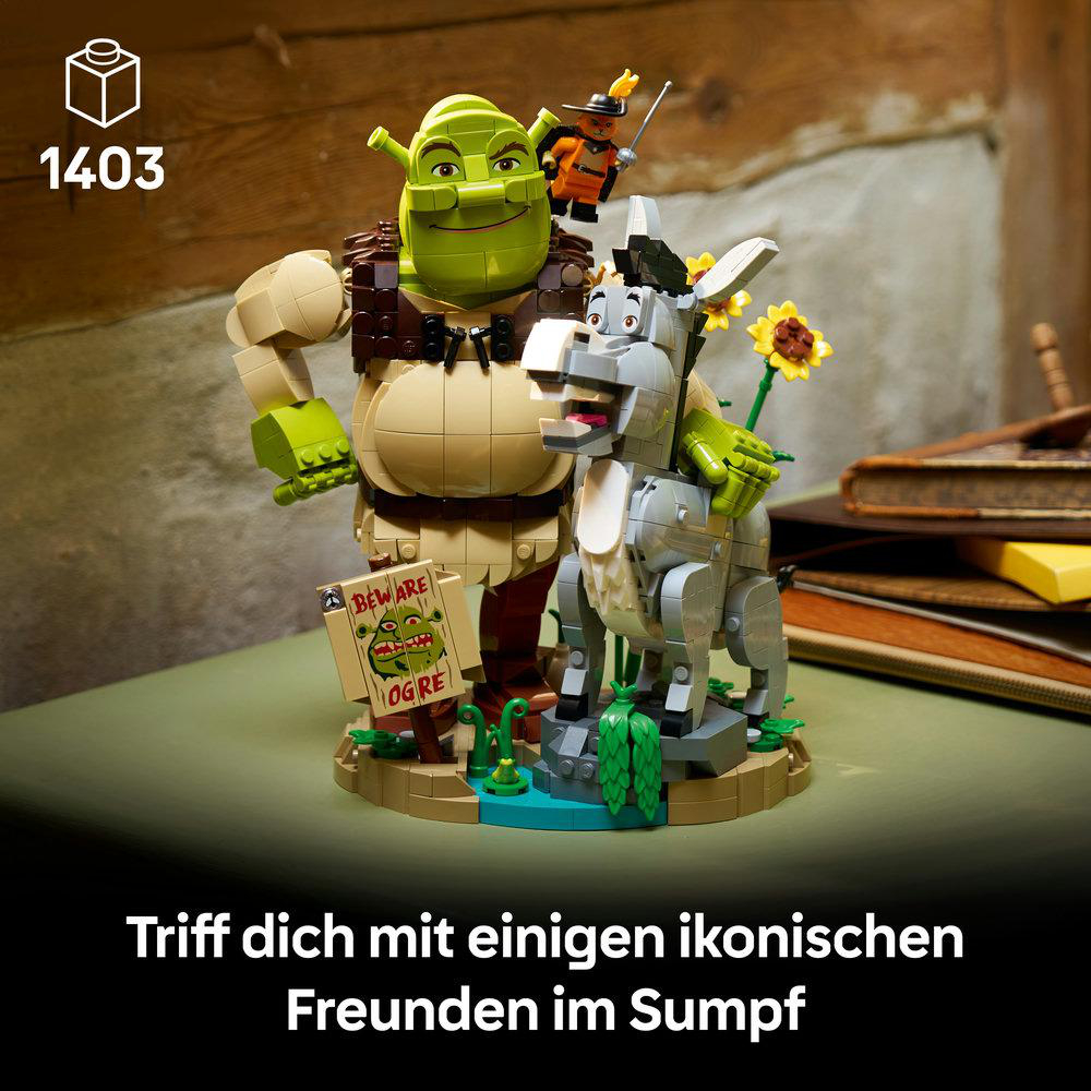 Lego-Figuren von Shrek, Esel und dem Gestiefelten Kater stehen im Sumpf.