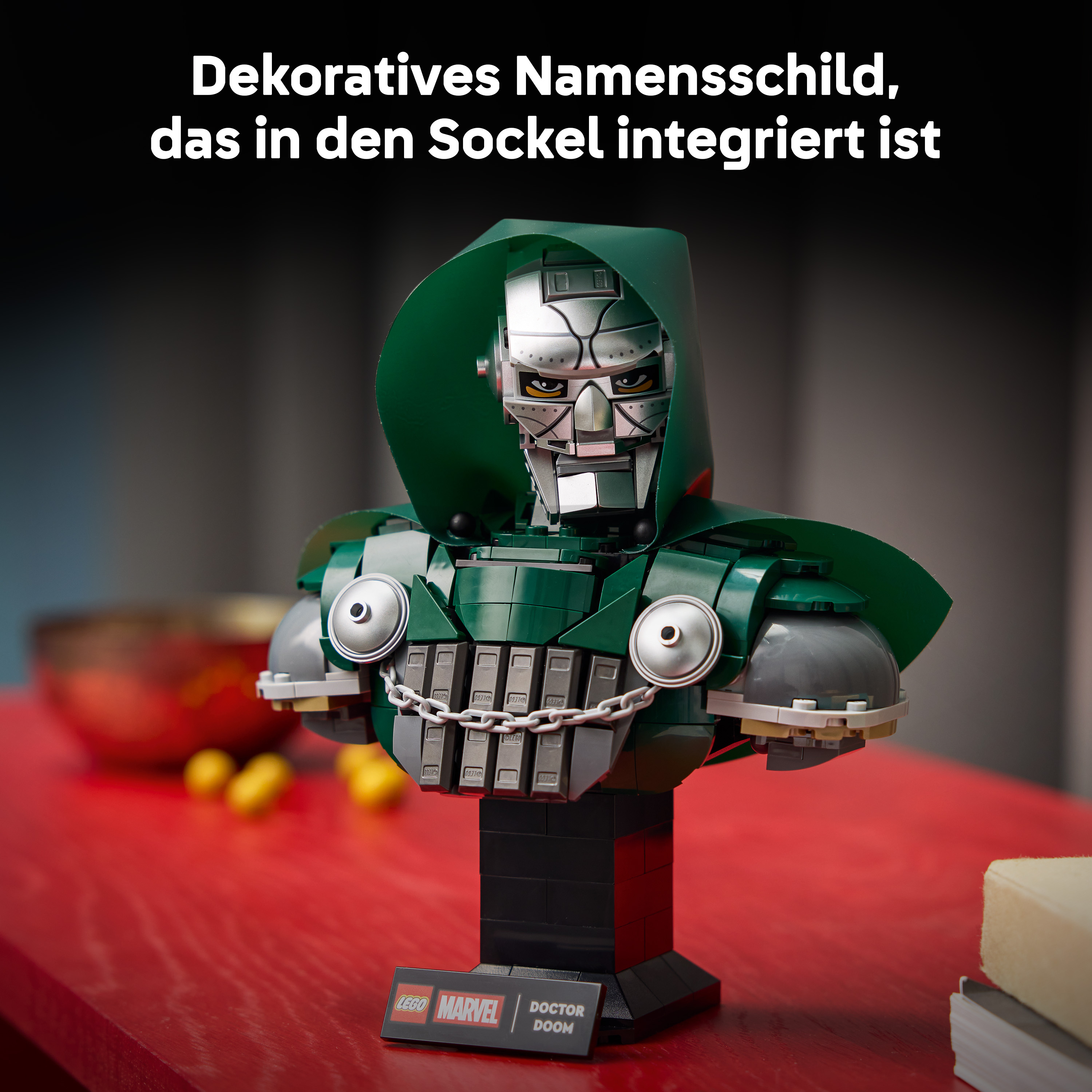Lego-Büste von Doctor Doom mit grünem Umhang und silberner Maske auf rotem Tisch.