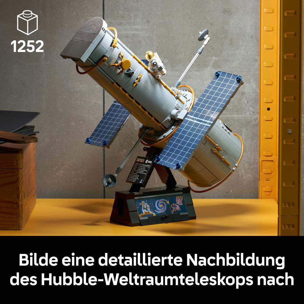 Ein detailreiches Lego-Modell des Hubble-Weltraumteleskops auf einem gelben Tisch mit Astronautenfigur.