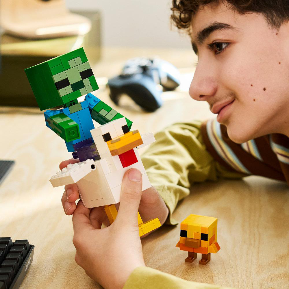 Ein Junge hält Minecraft-LEGO-Figuren, darunter ein Zombie auf einem Huhn.