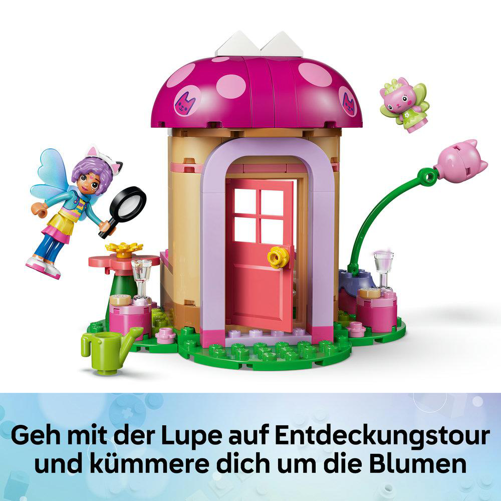 Lego-Pilzhaus mit rosa Dach, zwei Figuren mit Lupe, Blumen und grünem Zubehör auf weißem Hintergrund.