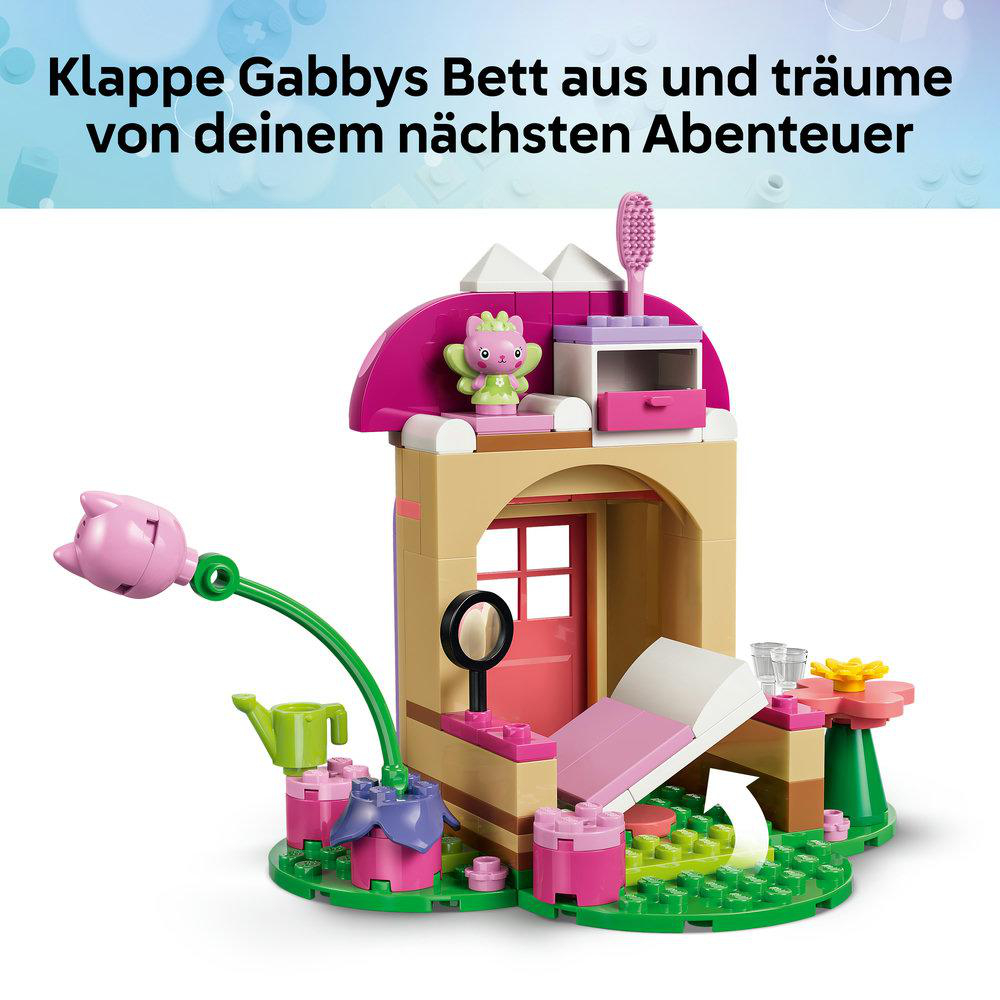 Ein Lego Gabby Dollhouse Schlafzimmer Set mit Bett, Figuren und Zubehör vor blauem Hintergrund.