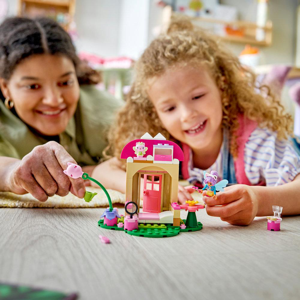 Eine Frau und ein Mädchen bauen zusammen ein farbenfrohes Lego-Haus auf dem Boden.