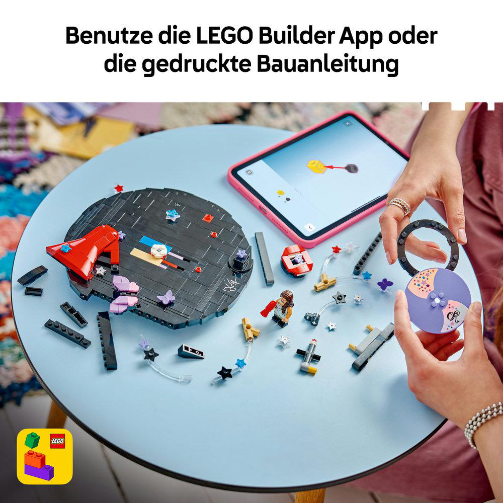 Eine Person baut ein LEGO-Set an einem blauen Tisch mit einer Anleitung auf dem Tablet.