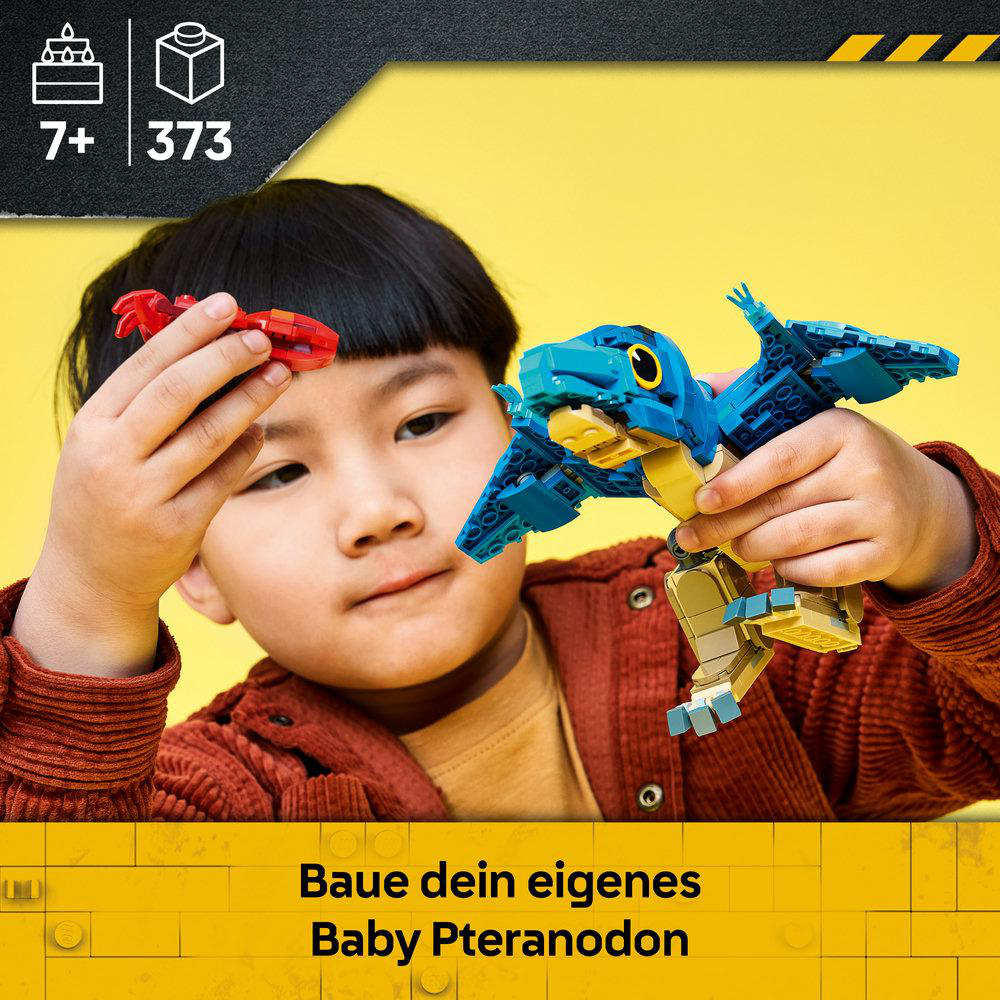 Ein Kind baut ein blau-gelbes LEGO Pteranodon-Modell vor gelbem Hintergrund.